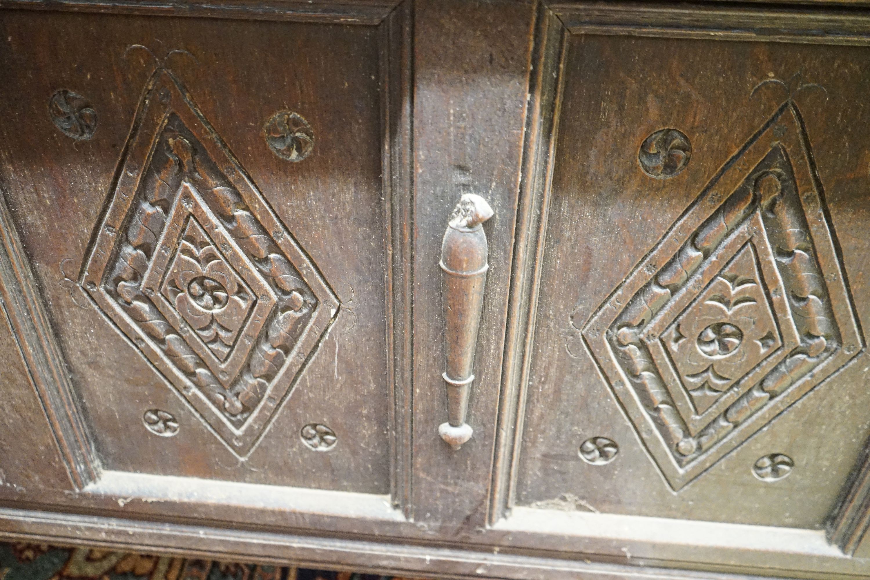 An early 18th century oak coffer, with four panel top and later carved and applied decoration, width 152cm, depth 63cm, height 74cm